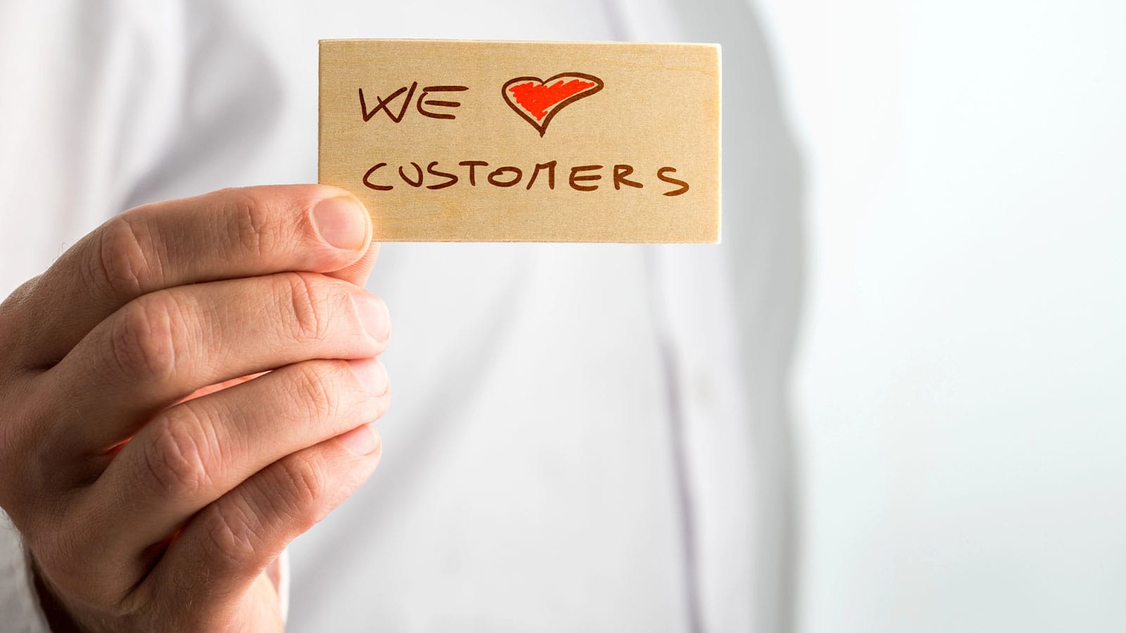 χέρι που κρατάει κάρτα "we heart customers" για εμπιστοσύνη πελατών