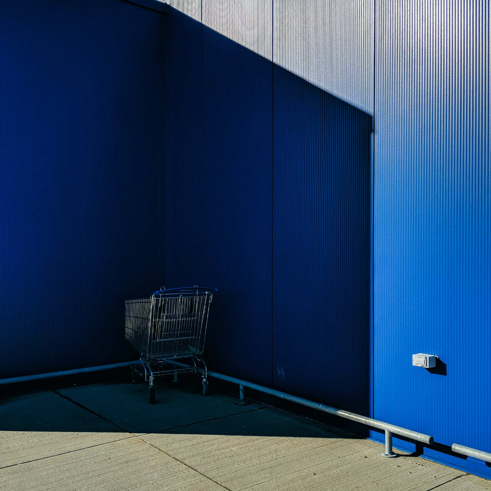 Καλάθι αγορών ξεχασμένο στη γωνία ενός μπλε τοίχου