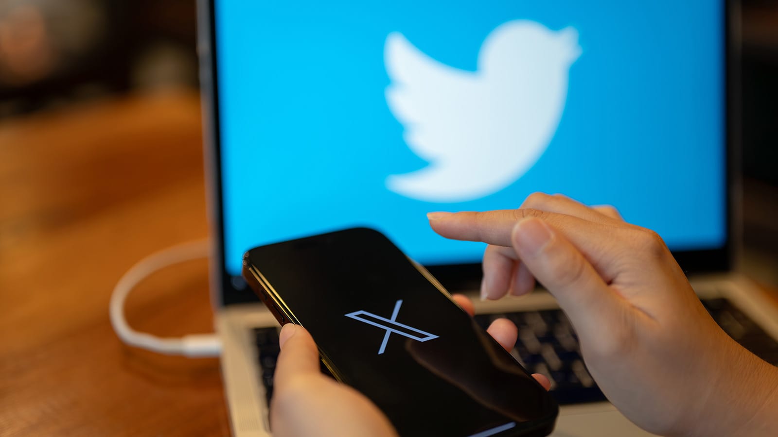 x (πρώην twitter) σε κινητό με χέρια και μπλε οθόνη σε blur