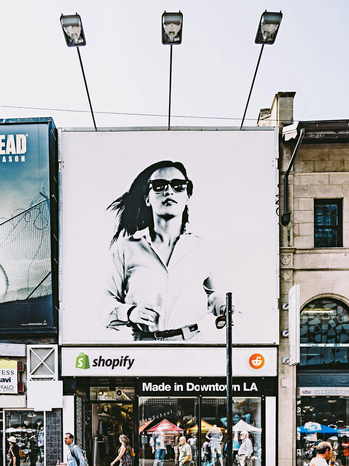 Ταμπέλα σε εμπορικό δρόμο με τα λογότυπα των Shopify Reddit Marketing