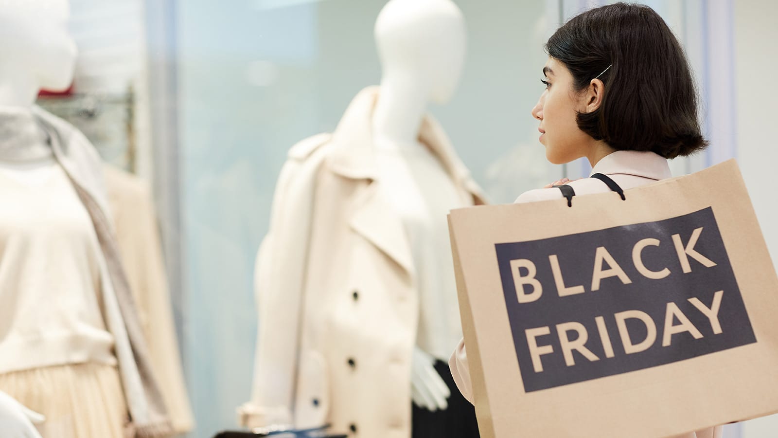 Γυναίκα που κοιτάει βιτρίνα με σακούλα από Black Friday