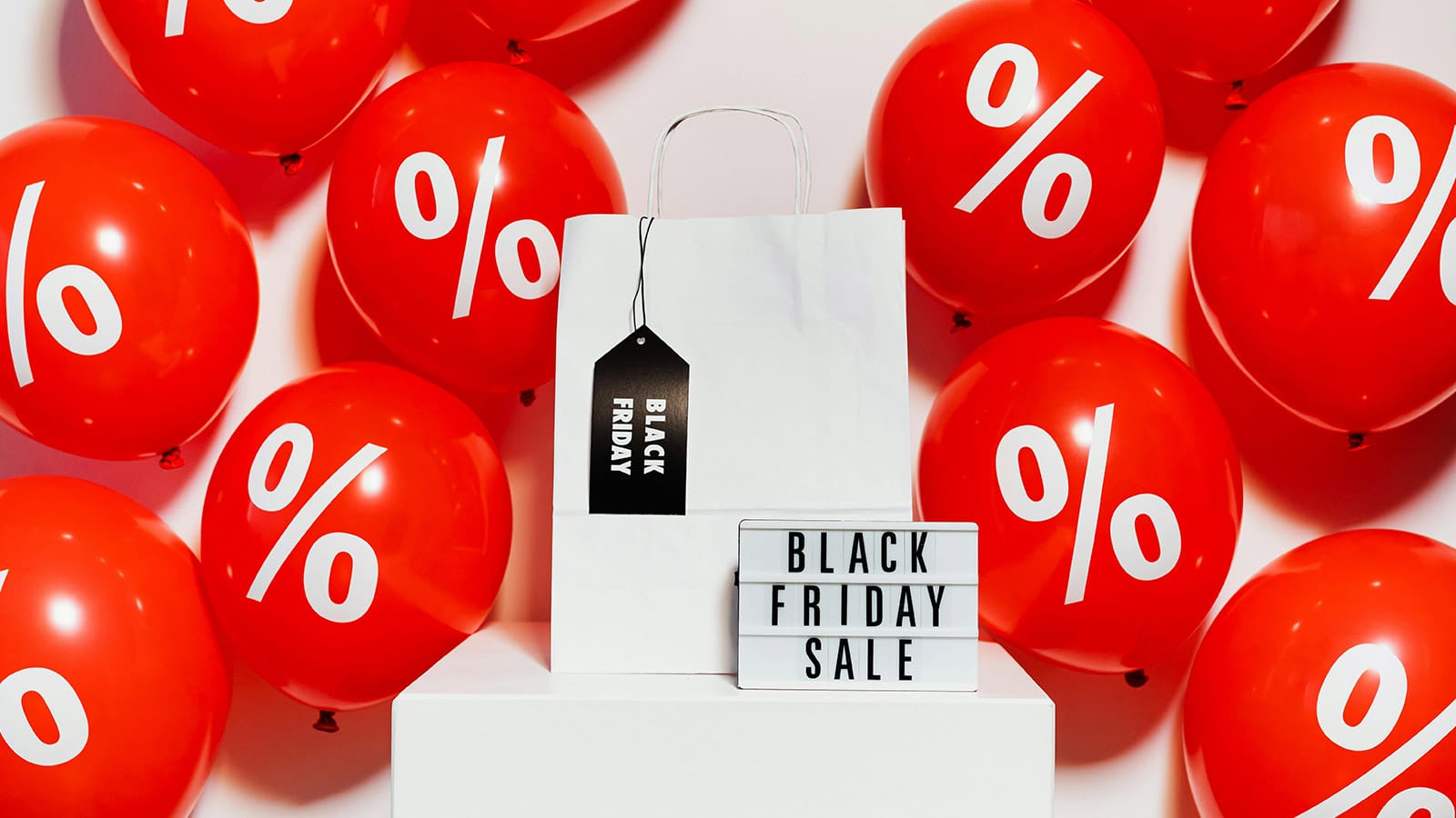 Μπαλόνια με εκπτώσεις Black Friday δίπλα σε σακούλα αγορών