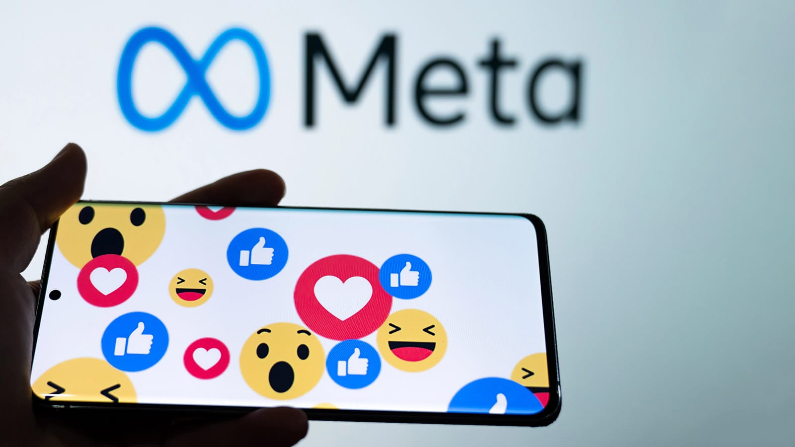 Reactions σε οθόνη κινητού μπροστά από το λογότυπο της Meta