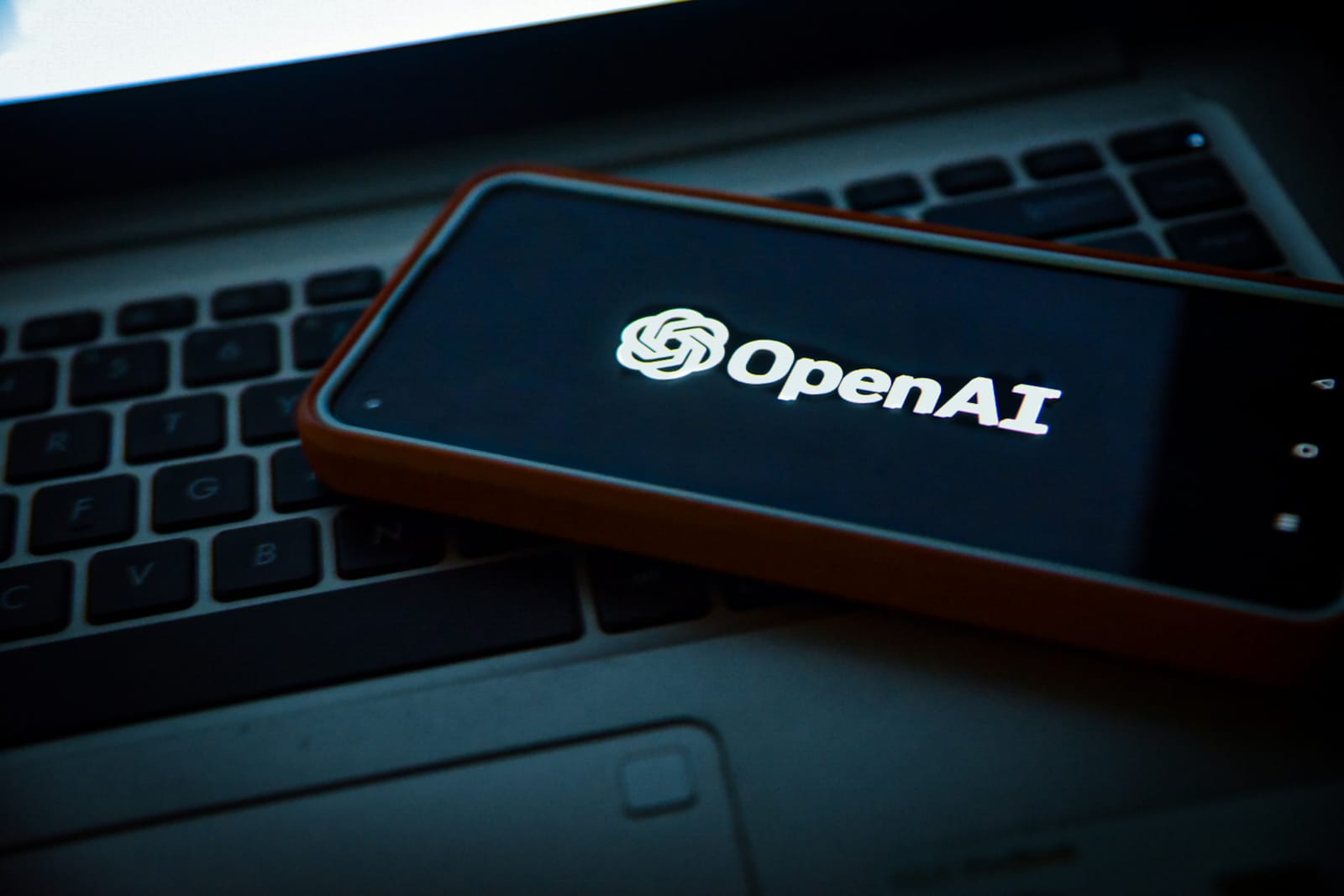 Κινητό πάνω σε λάπτοπ με οθόνη το λογότυπο της OpenAI