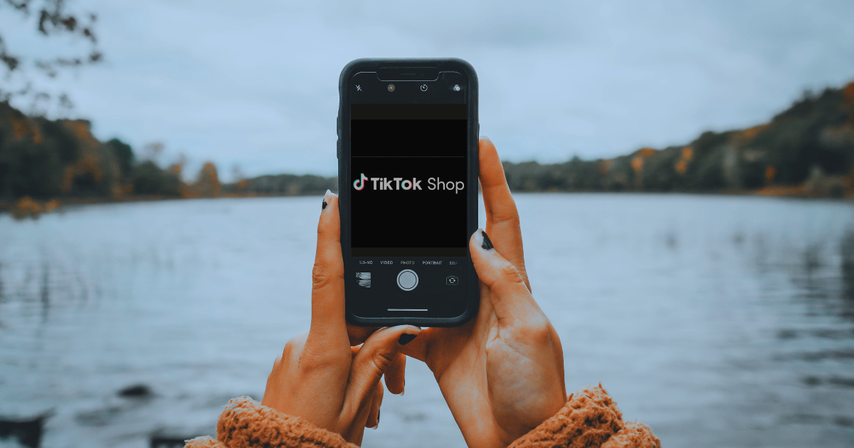 ένδειξη του tiktok shop σε κινητό που κρατάνε δύο χέρια με φόντο σε blur