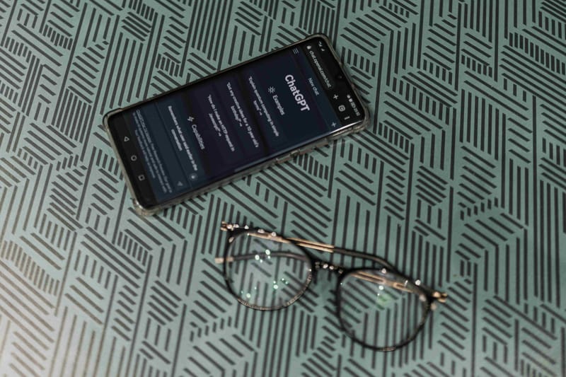 Η σελίδα αναζήτησης του ChatGPT σε mobile δίπλα σε γυαλιά μυωπίας