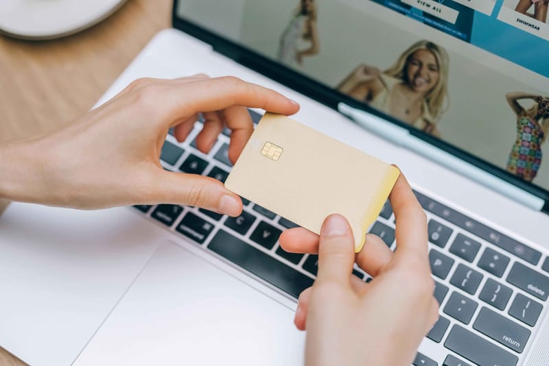 Κάρτα αγορών σε χέρια μπροστά από λάπτοπ με eshop